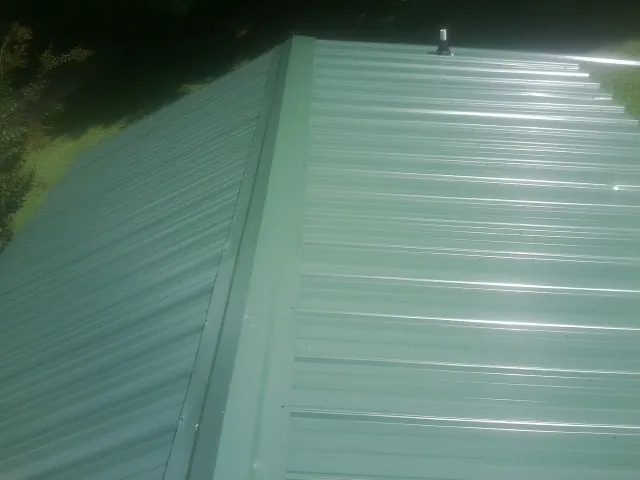 New green metal panels meeting at the ridge of a roof — Flat Roof Repair work by our crew in Ranger