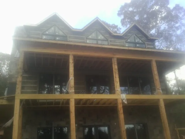 Dormers and porch framing on a large log home under construction — Roof Coating work by our crew in Ranger