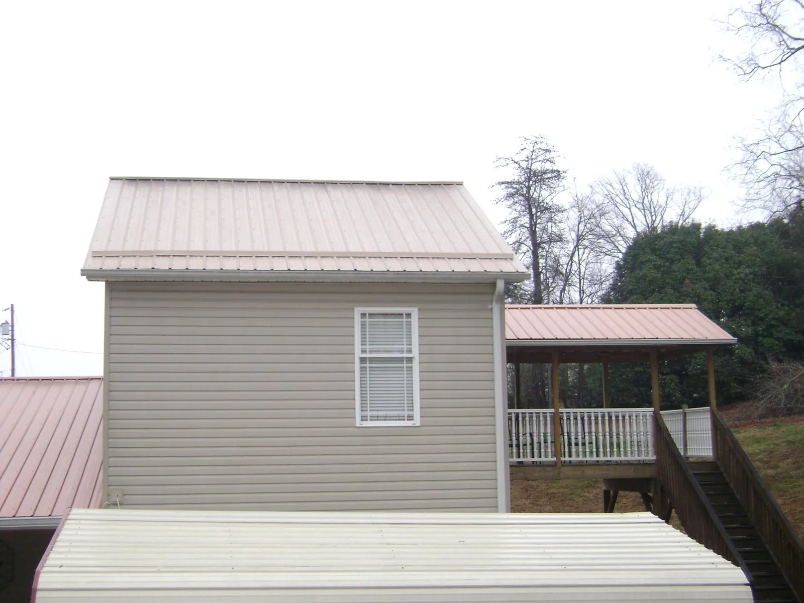 Tan metal roofs on a two story addition and attached porch, from a Roof Replacement job in Ranger