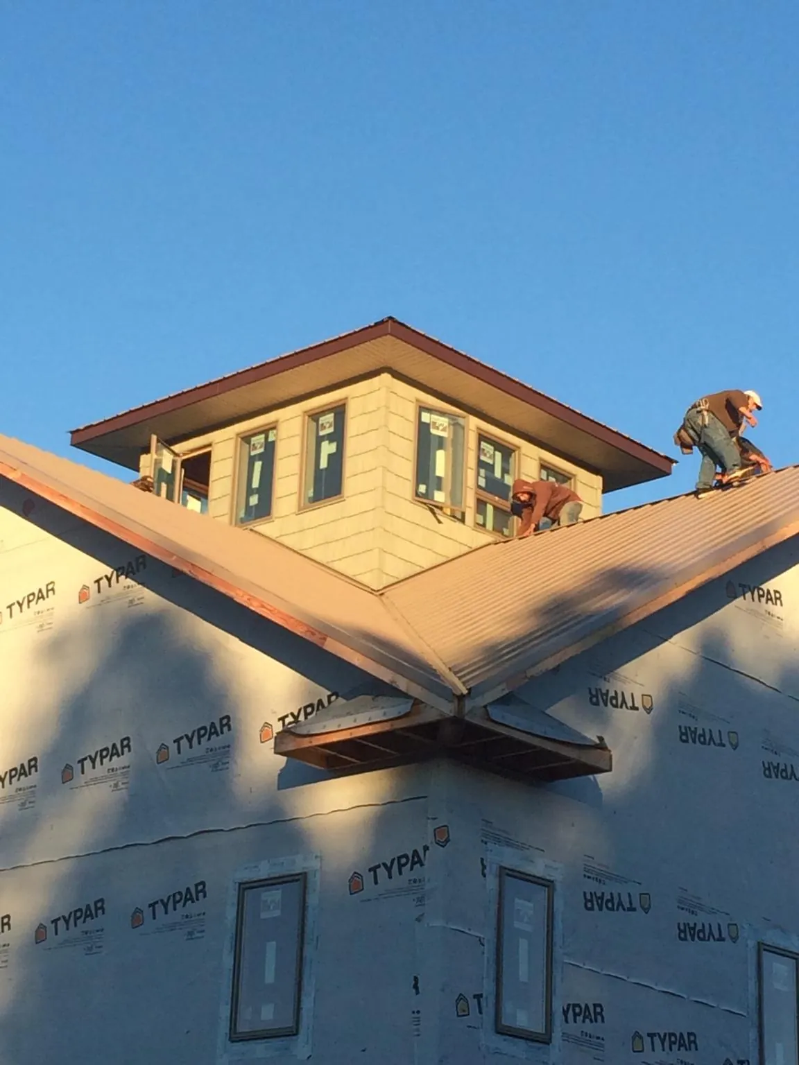 Roofers working around a rooftop cupola on a new metal roof at sunset — Roof Waterproofing in Ranger by Roofing Brothers